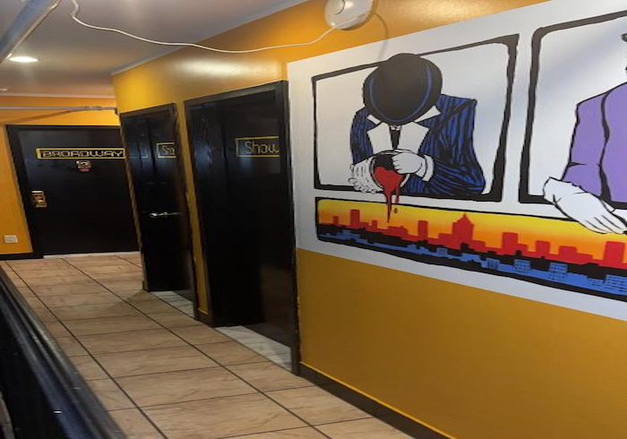 Hallway with yellow walls, black doors, and a large mural of a person writing above a city skyline.