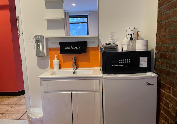 Small kitchenette with sink, mini fridge, microwave, and orange backsplash in a compact office area