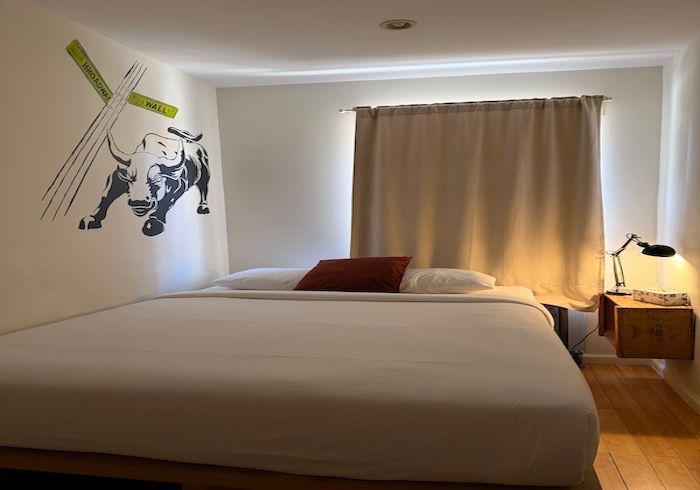 Minimal bedroom with a large bed, wall art, curtained window, and bedside lamp