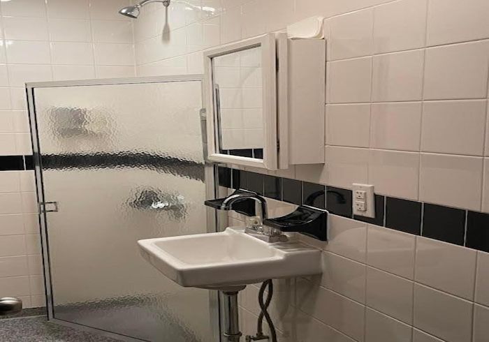 Small bathroom with a wall-mounted sink, mirror cabinet, and frosted shower enclosure.