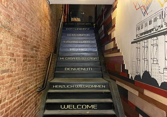 Narrow stairway with colorful text steps and brick walls in a hallway