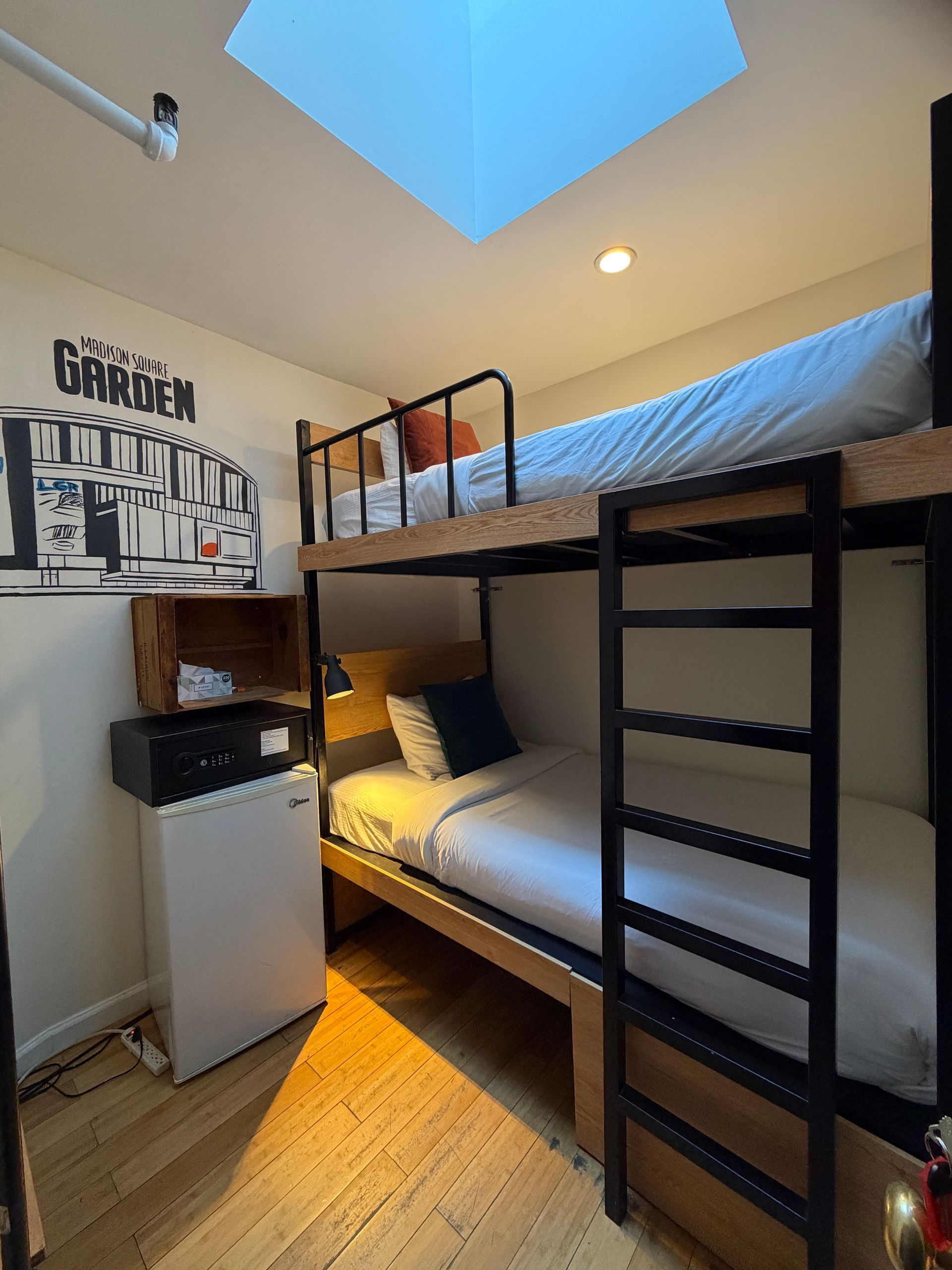 Small bedroom with black bunk bed, skylight, desk, and wall art.