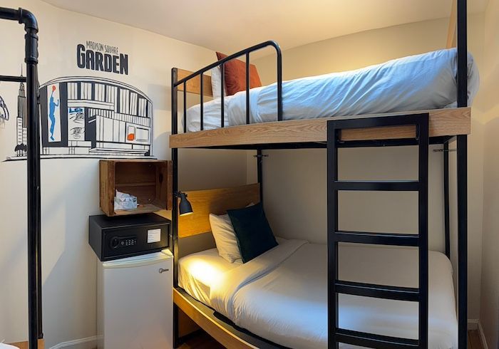 Modern dorm room with bunk beds, ladder, shelving, and warm lamp light