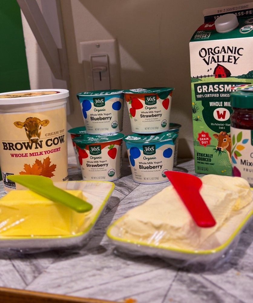 Assorted dairy products and a brown cow milk carton arranged on a kitchen counter with green and red utensils