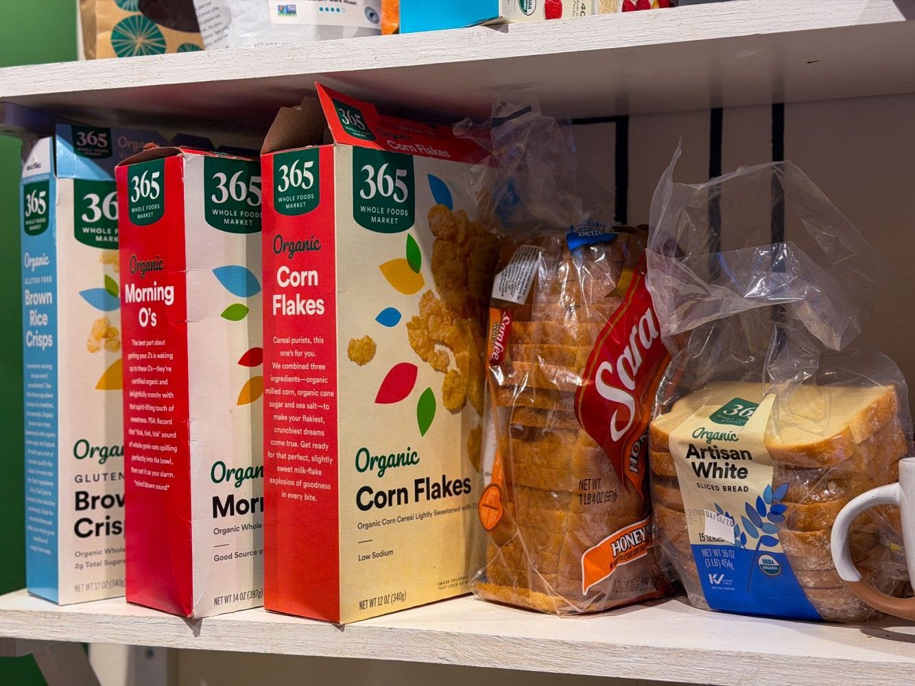 Pantry shelf with cereal boxes, bread, and a loaf of white bread on the right.