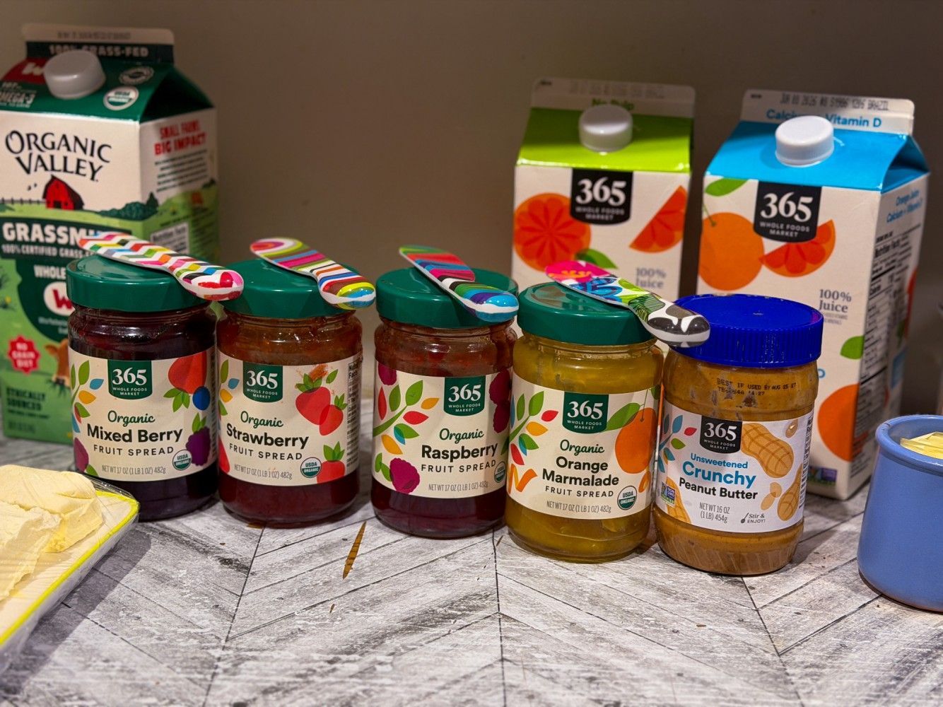 Assorted jars and cartons of organic fruit spreads and juice on a kitchen counter