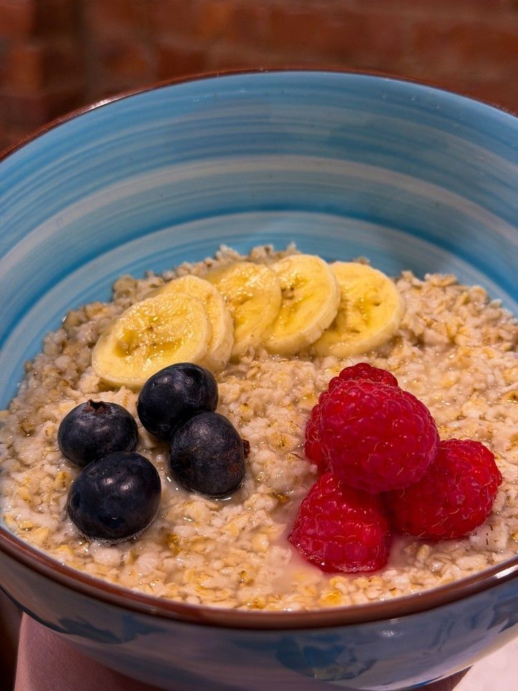 Bowl of oatmeal topped with banana slices, blueberries, and raspberries