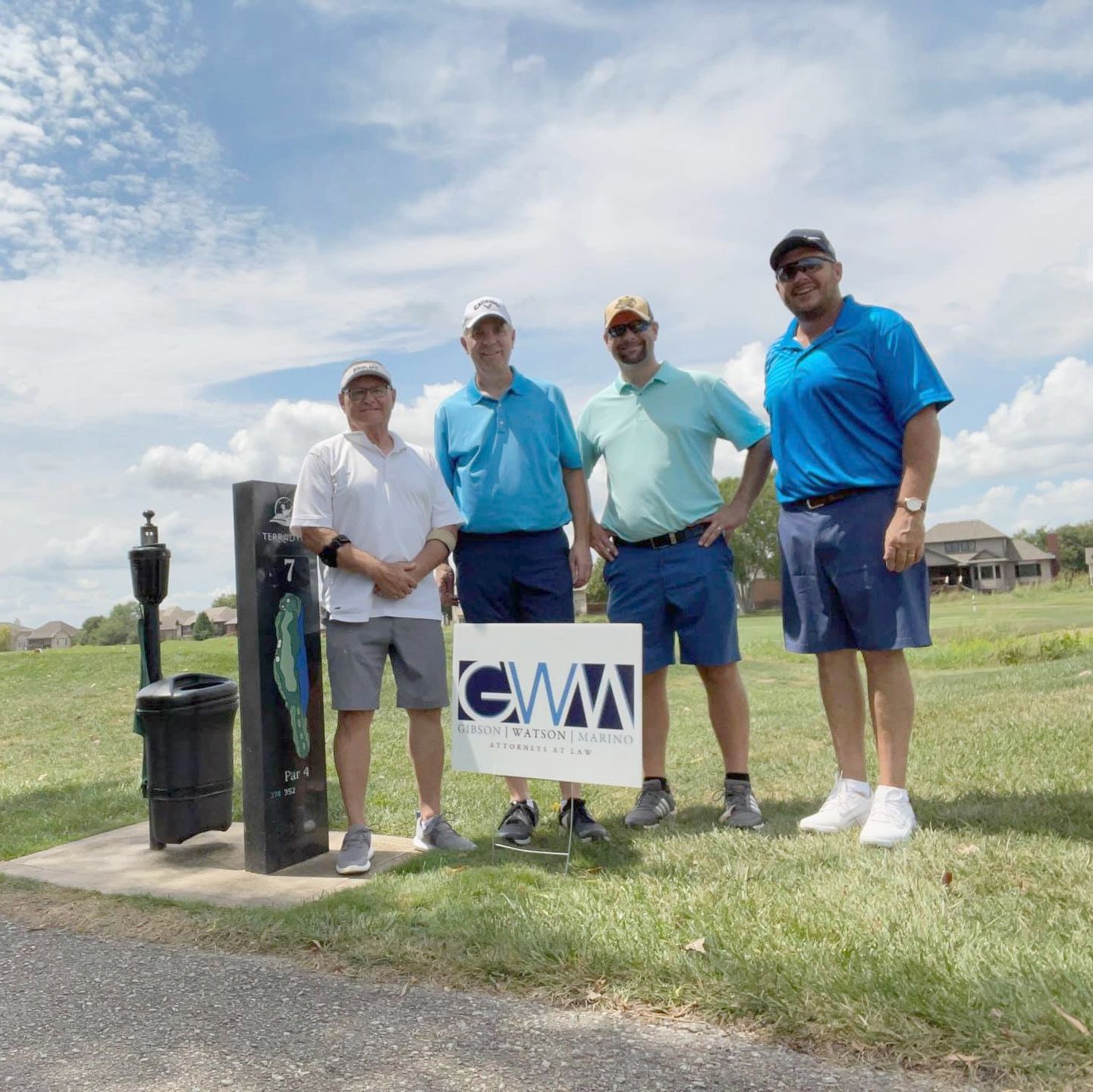 Four golfers stand by the sign marking the gold hole they sponsored