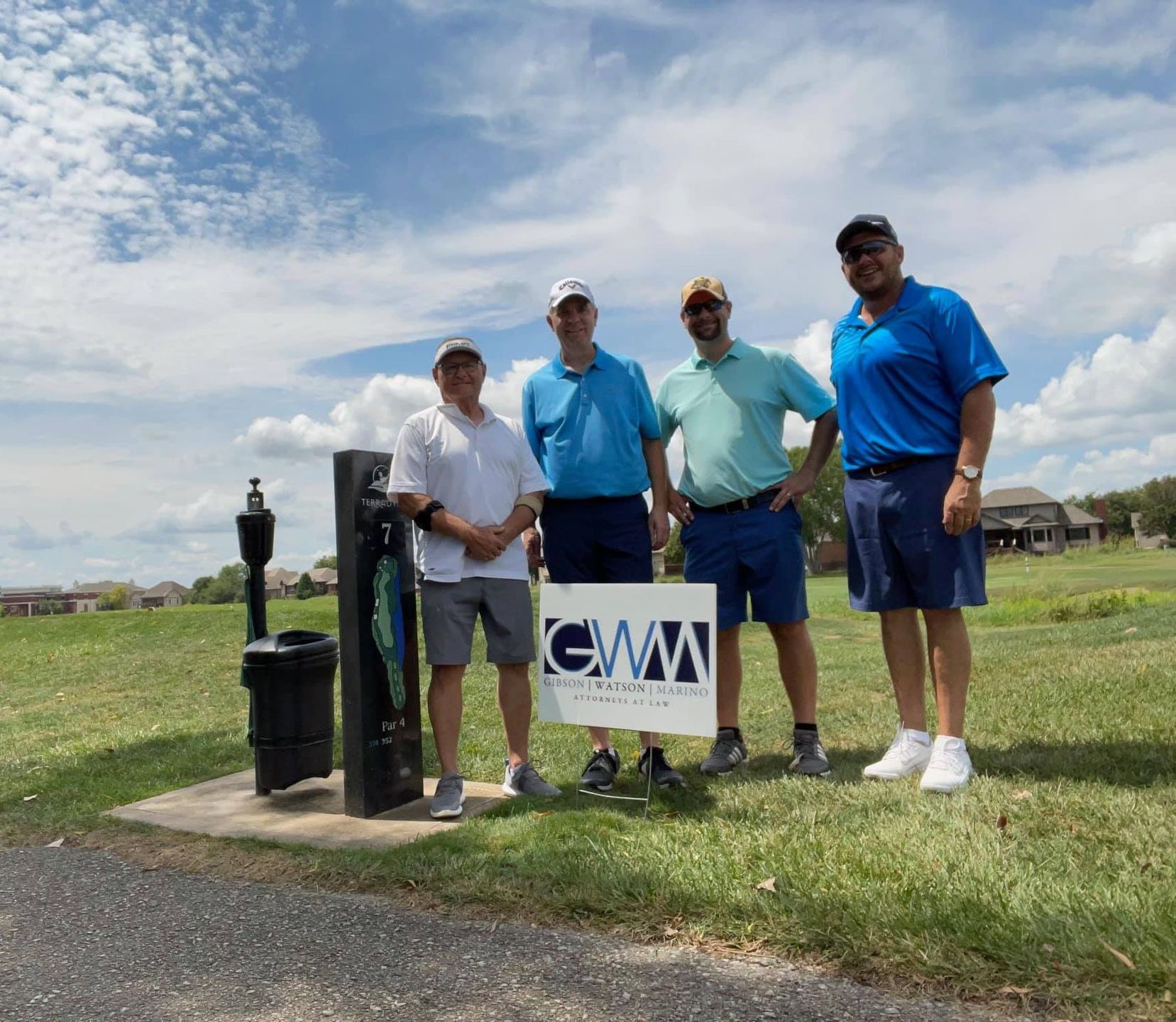 golfers pose by the hole they sponsored