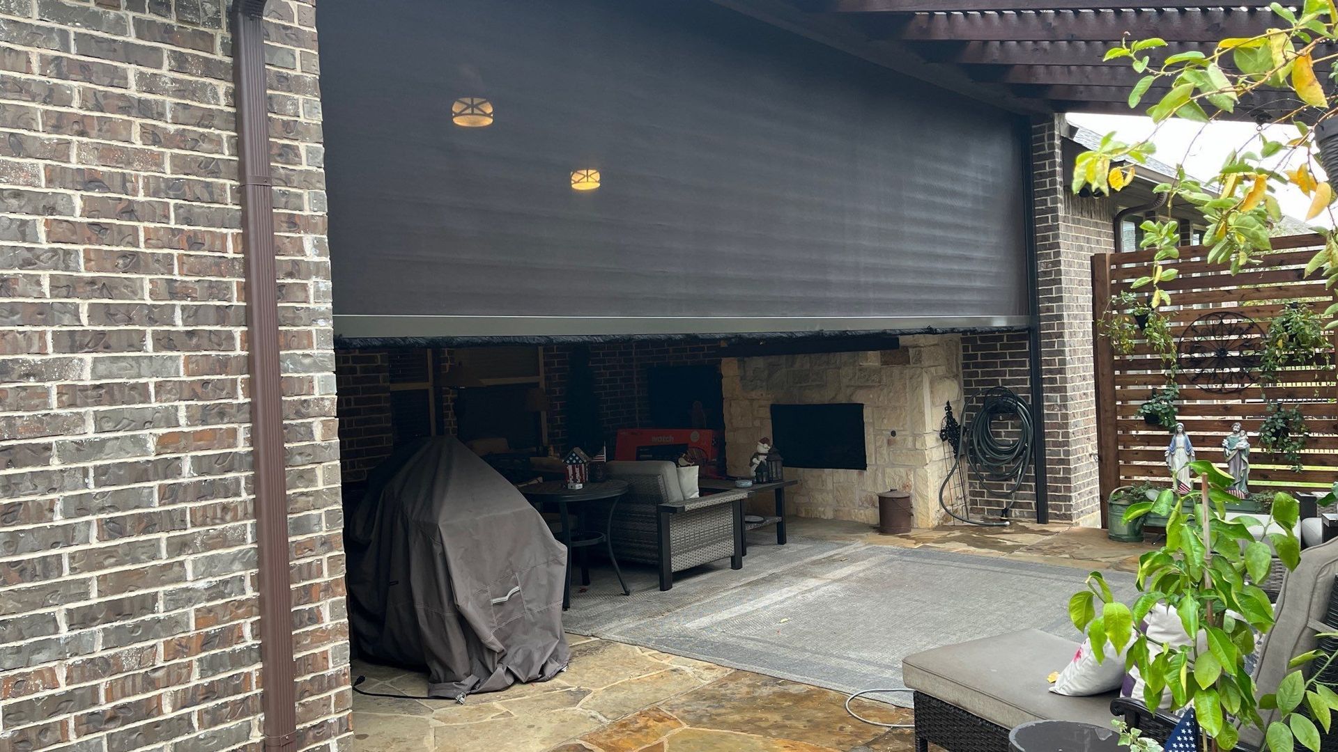 Outdoor patio with retractable shade, brick columns, and a stone patio.