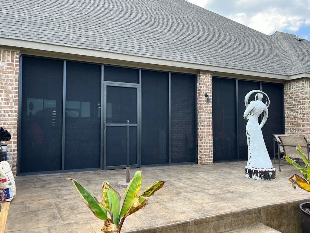 Screened-in patio with brick exterior and dark screens. A white statue stands nearby.
