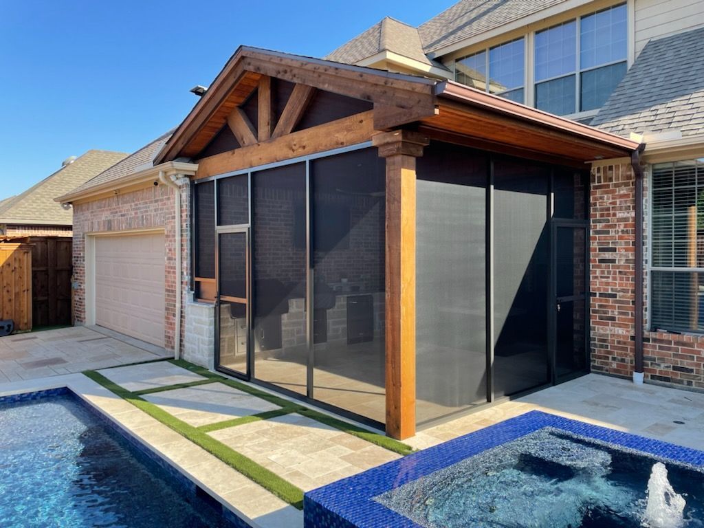 Screened-in porch beside a pool; brown wood, black screens, brick house with blue water.