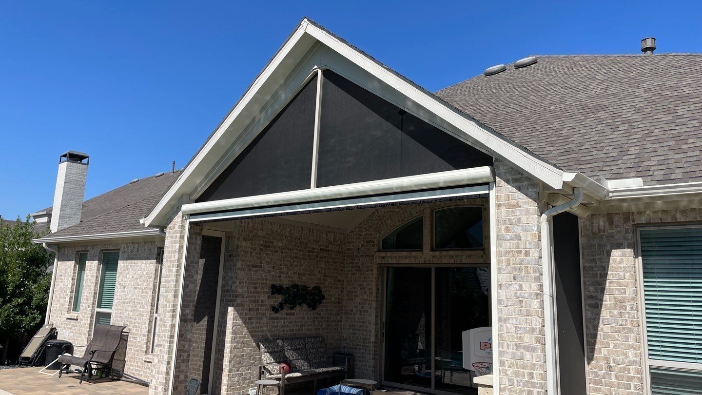 A brick house with a dark screened porch, angled roof, and a clear blue sky.