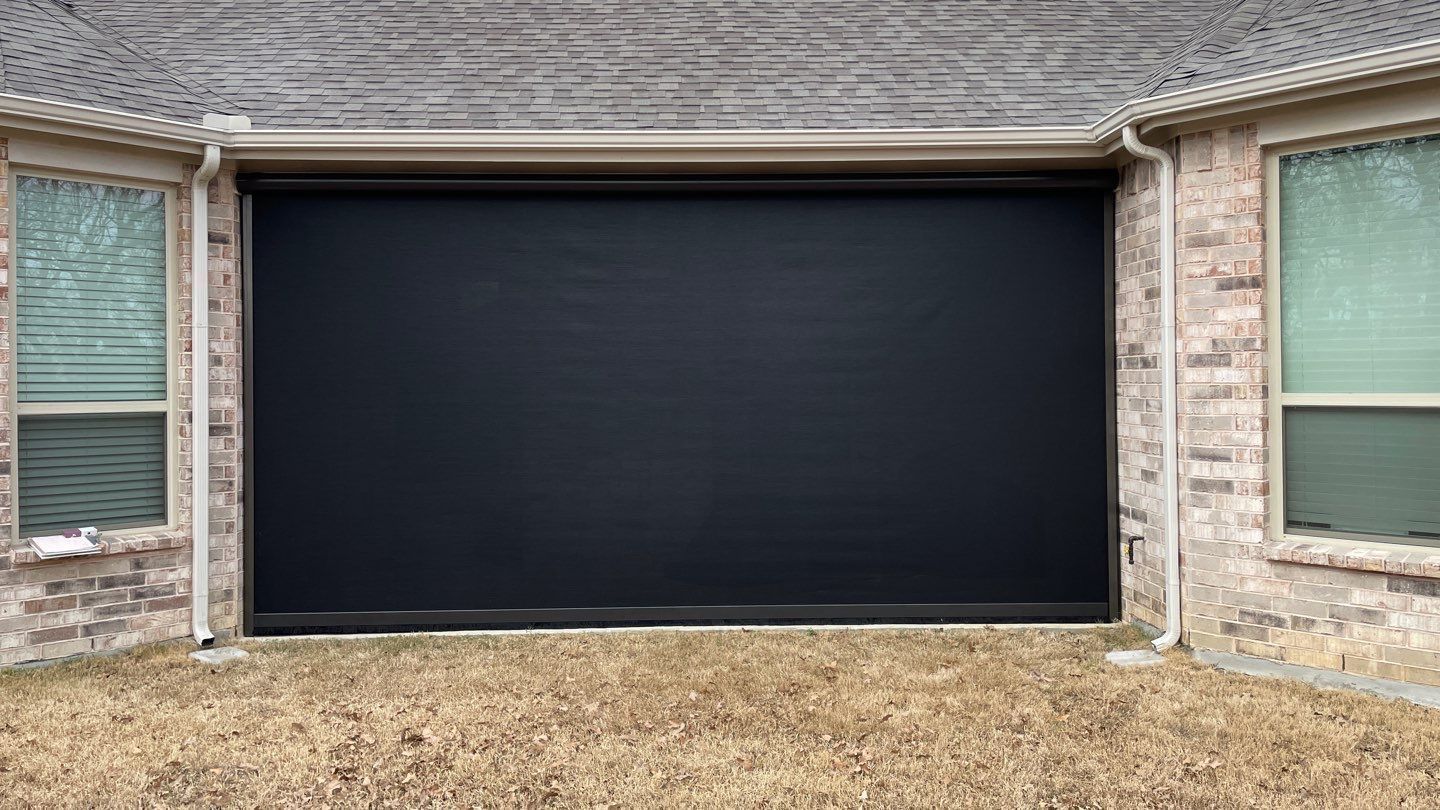 Black patio screen installed between brick walls and under a roof.