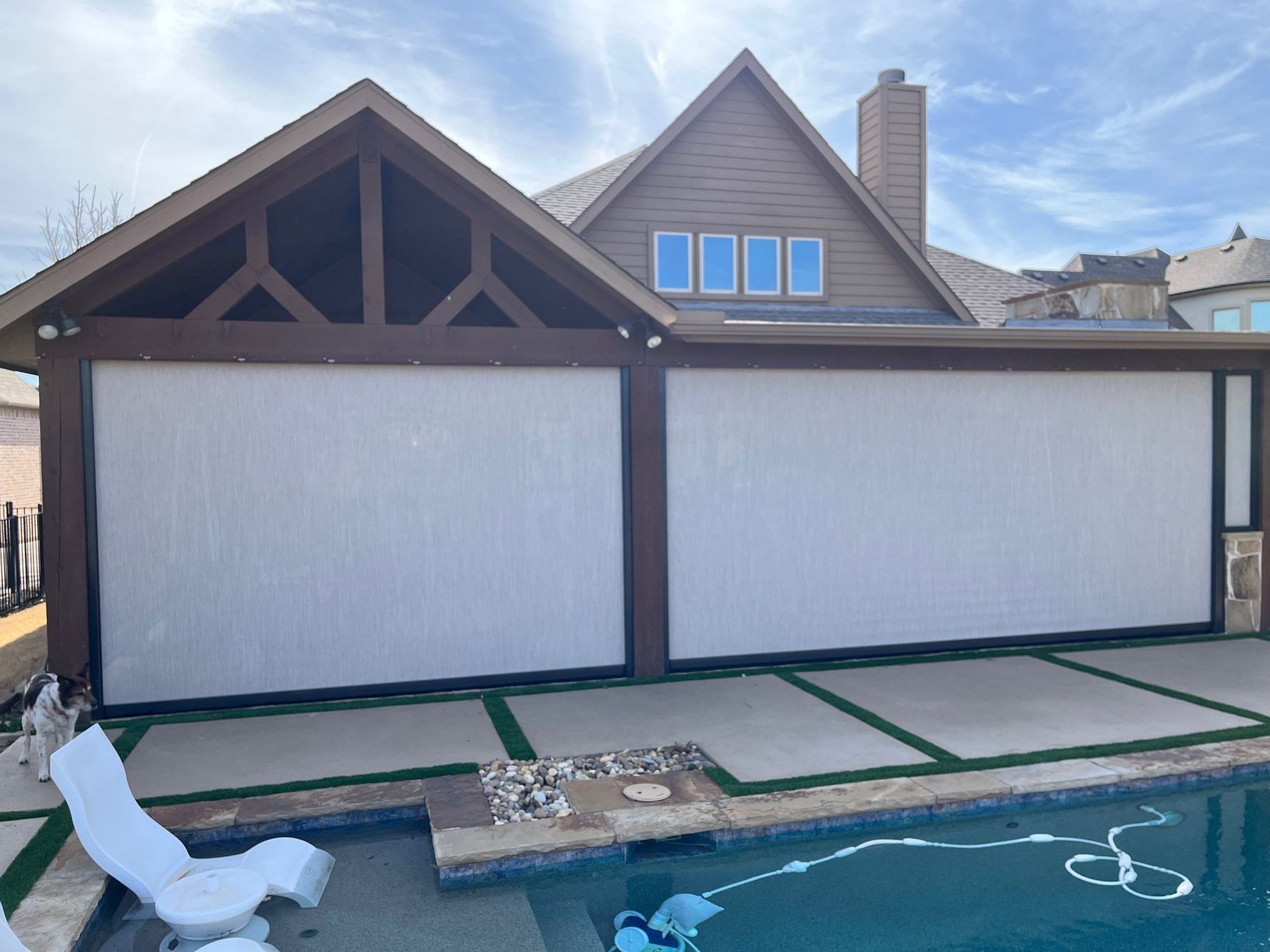 Exterior of a house with a pool and covered patio. The patio has large white screens.
