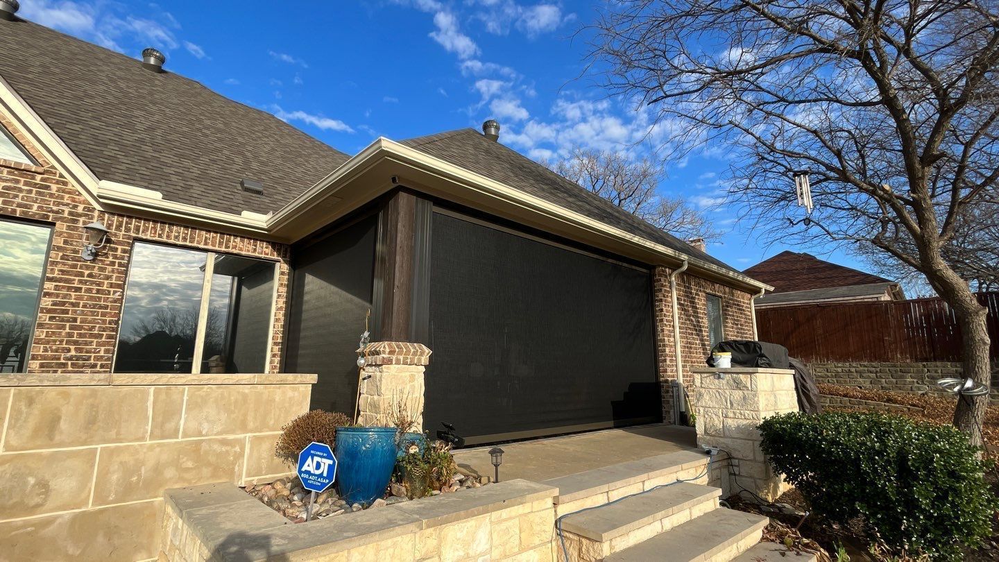 Covered patio with a dark screen, brick house, and steps.