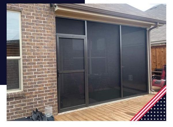 Screened-in porch with dark metal frames, attached to a brick home. A door is on the left, deck below.