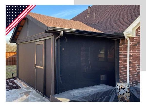 Enclosed brown patio with screens attached to a brick house. Includes rain gutter and flag.
