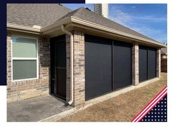 Brick patio enclosure with black sun shades, beige trim, and a window.