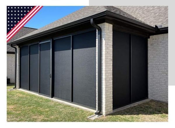 Outdoor patio enclosed with black sliding panels; brick walls, green grass.