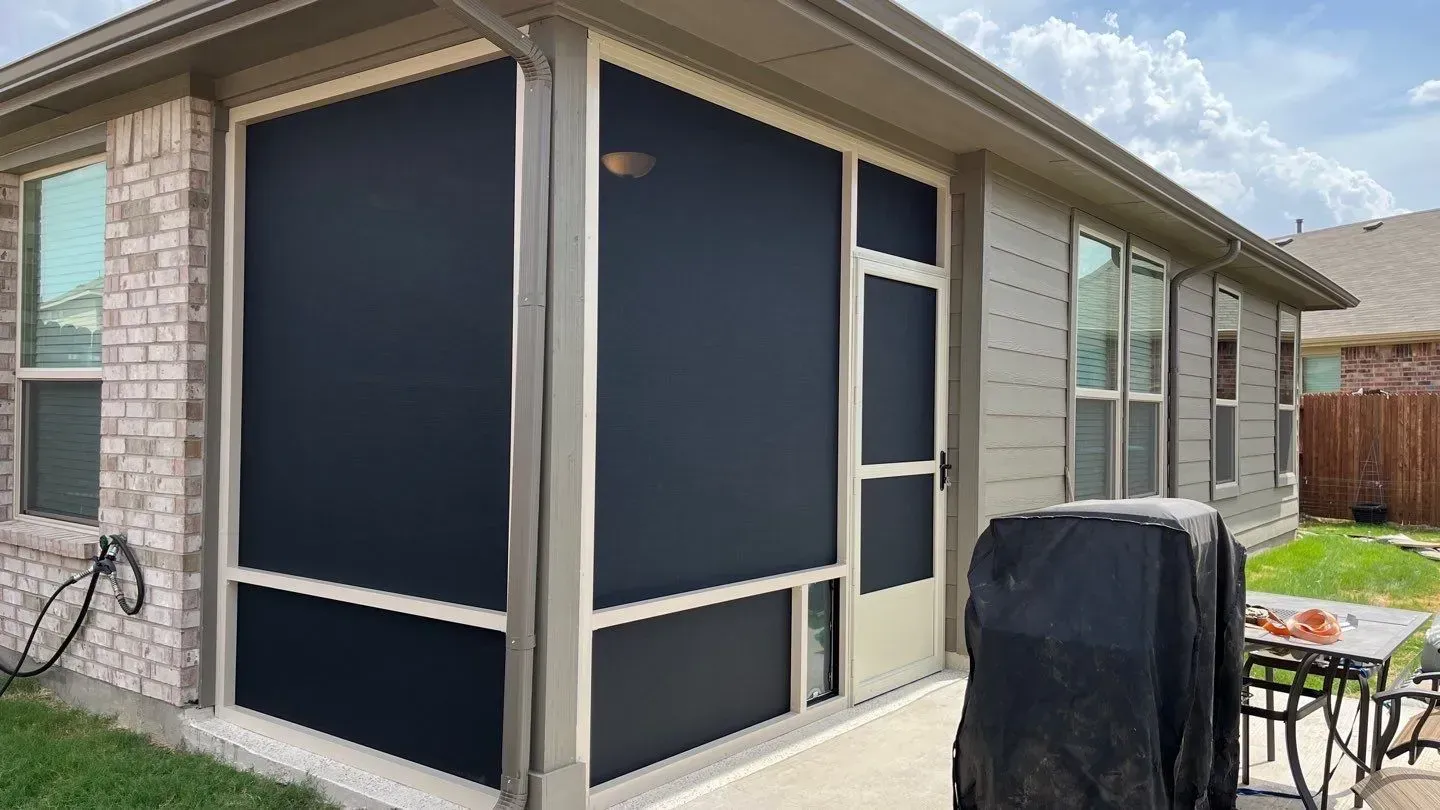 Screened patio enclosure with dark blue panels on a house exterior and a grill nearby