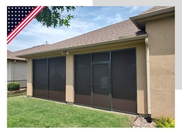 Screened-in porch attached to a tan house with the American flag in the corner.
