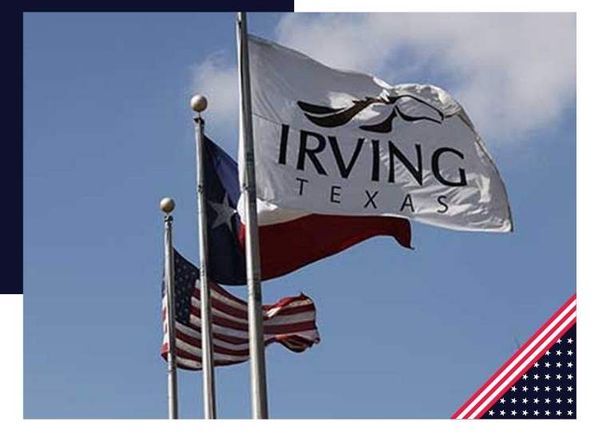 Flags of the United States, Texas, and Irving, TX, wave against a blue sky.
