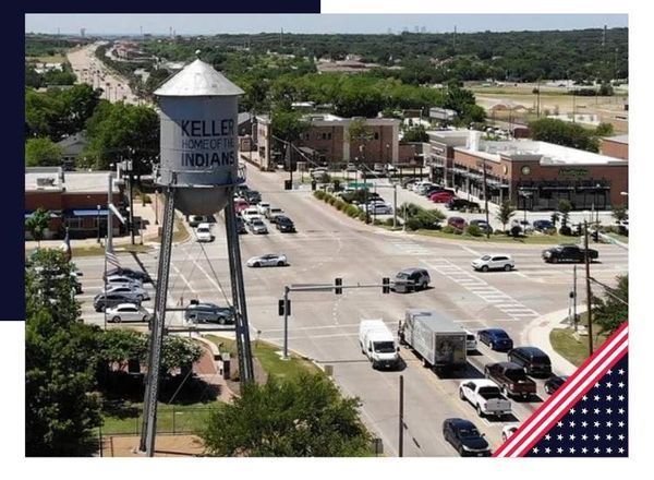 Water tower in Keller, Indiana, overlooking a busy intersection with cars and buildings under a blue sky.
