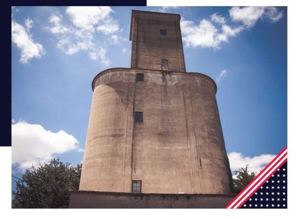 Concrete silo tower against a bright blue sky with scattered clouds.