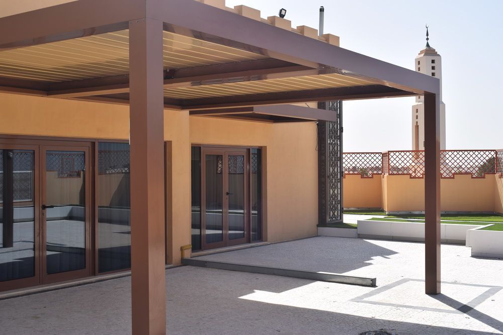 Brown pergola shading a patio outside a building.