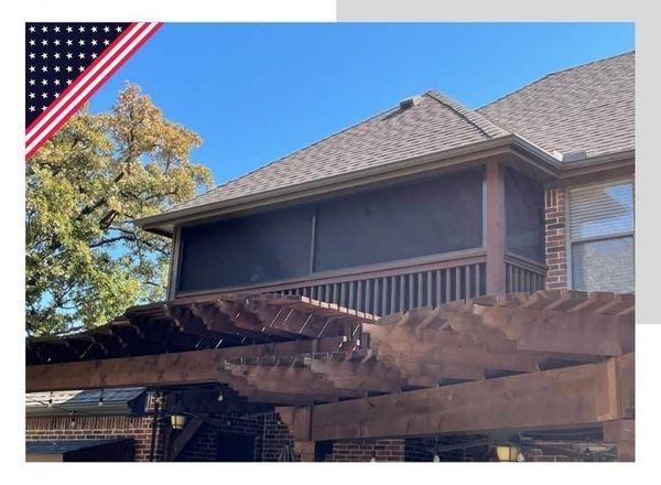 Screened porch with dark screens, brown wooden frame, attached to a brick house. Pergola below.