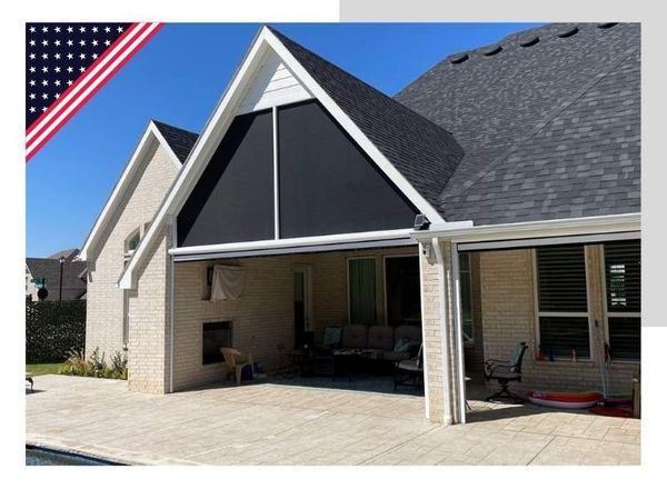 Black shade on house gable. American flag graphic in corner. Patio with furniture and fireplace.