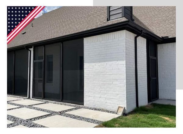 Screened-in porch on a white brick house with dark trim and a paved patio.