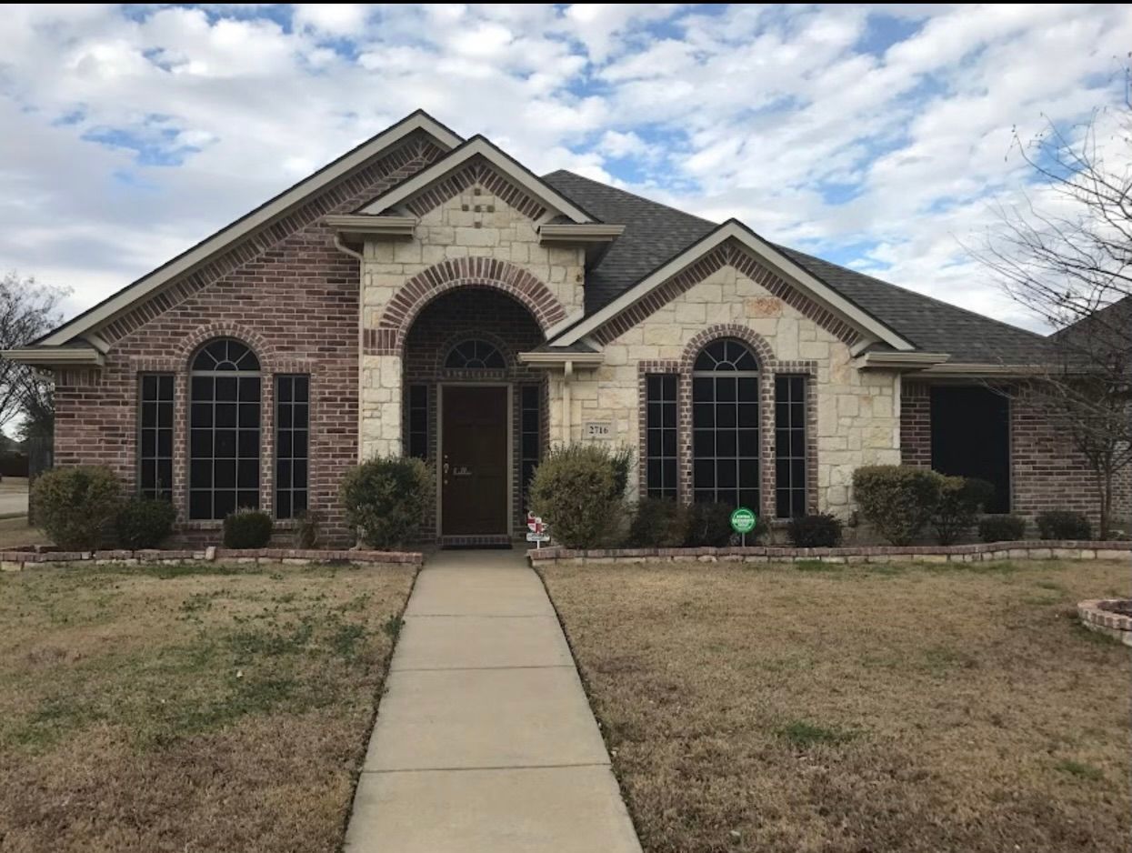 Brick and stone house with a walkway leading to a dark wood front door.