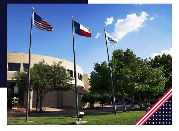 Three flags flying in front of a building: U.S., Texas, and a third with blue and white design; sunny day.