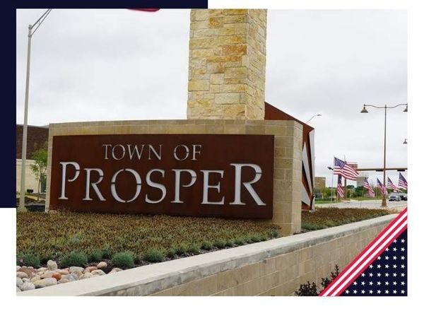 Sign for Town of Prosper with stone tower and flags in background.