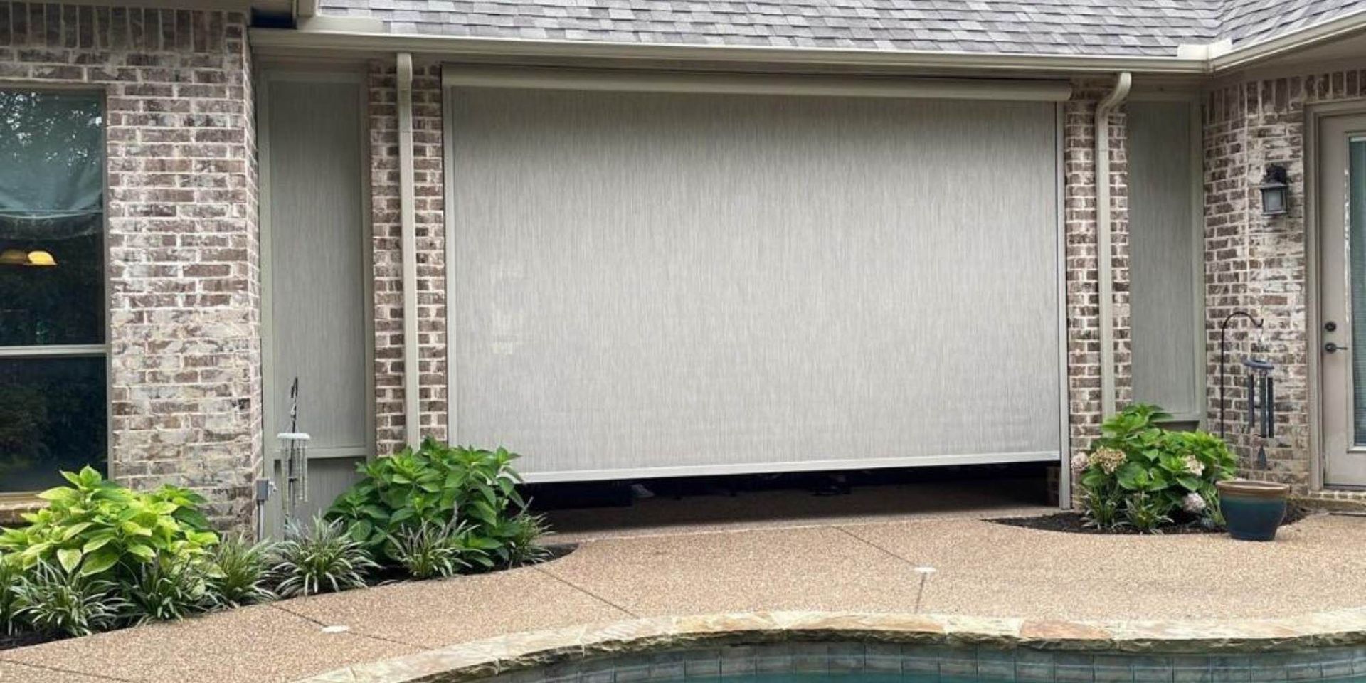 Motorized solar screen lowered over a poolside patio