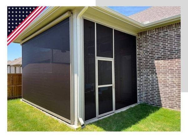 Enclosed outdoor area with black screens, white trim, and a brick wall. American flag in the corner.