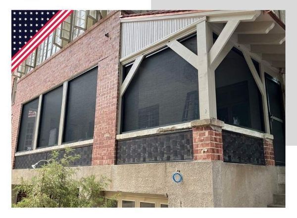 Exterior of a two-story brick building with dark window screens; American flag in the upper left corner.
