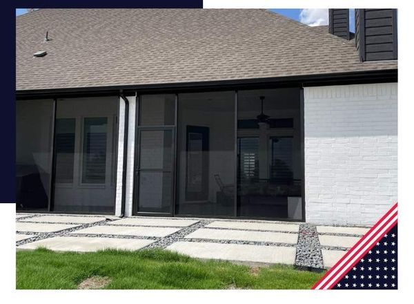 Screened-in porch with concrete patio, grass lawn, and white brick wall, under a roof.