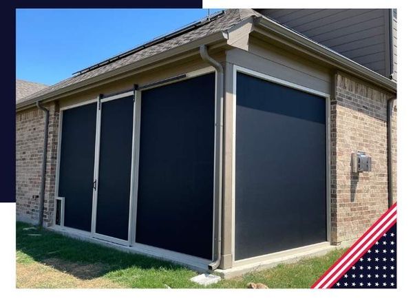 Black outdoor shades on a brick house, protecting an outdoor space.
