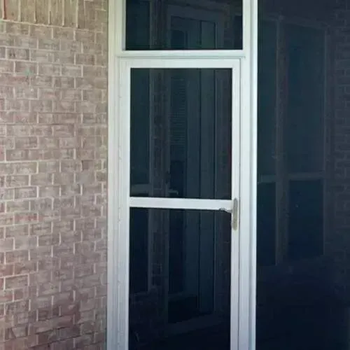 White-framed screen door on a brick house porch with a dark interior beyond