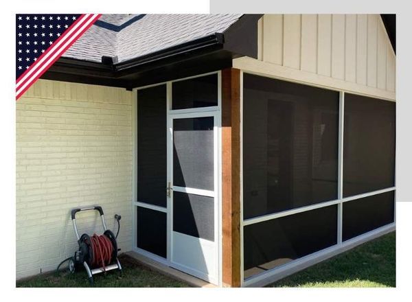 Screened-in porch attached to a light brick building. Features screen door, white trim, dark screens, and a hose reel.