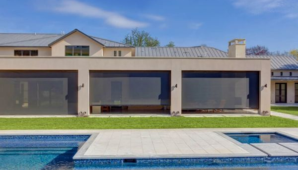 Modern house patio with large glass doors and a swimming pool in front