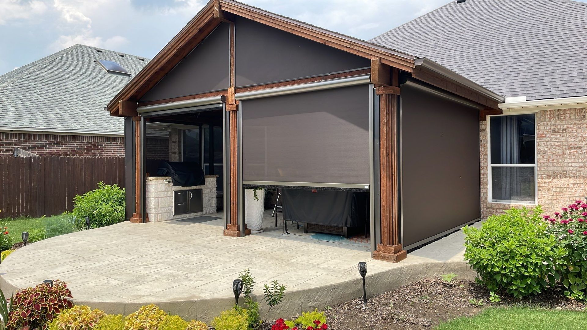 Brown patio enclosure with retractable shades, wooden beams, and a concrete patio.