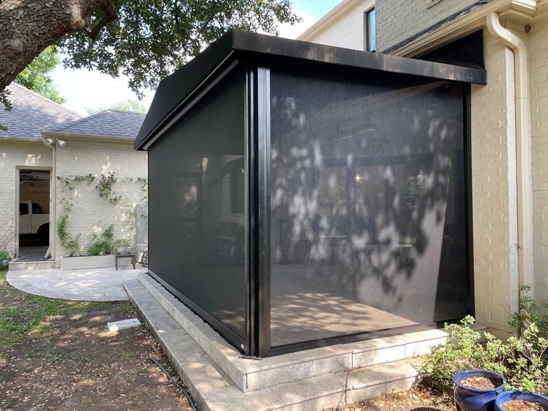 Black screened-in patio with dark framing attached to a light beige house. Concrete steps lead to the screened area.