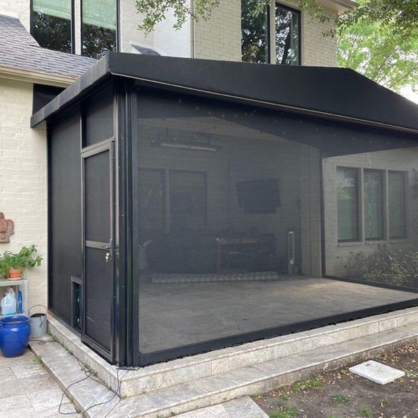 Black screened patio enclosure on a stone patio beside a house