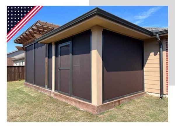 Brown screened patio enclosure with door; beige trim, built onto a house, against green grass.