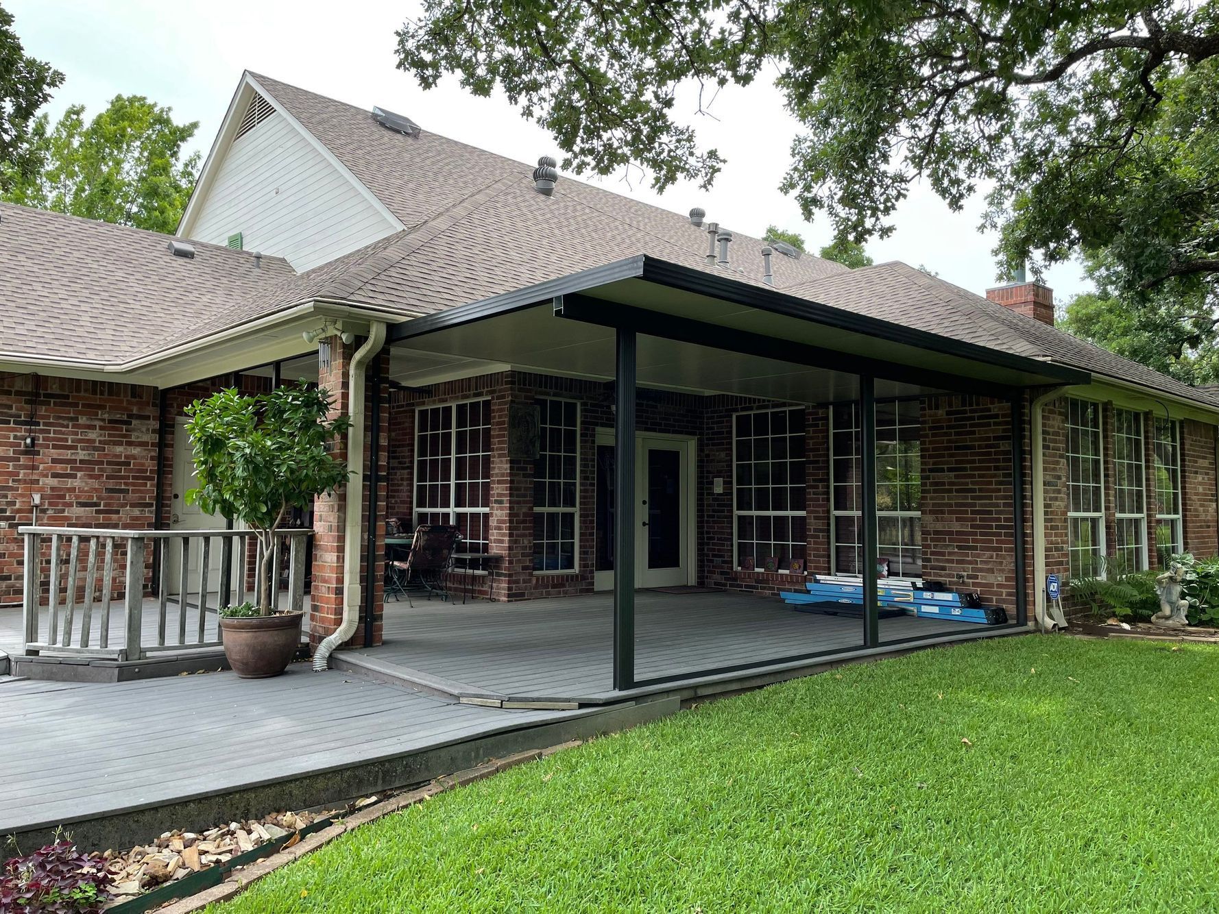 Brick house with patio and awning, green lawn in foreground.