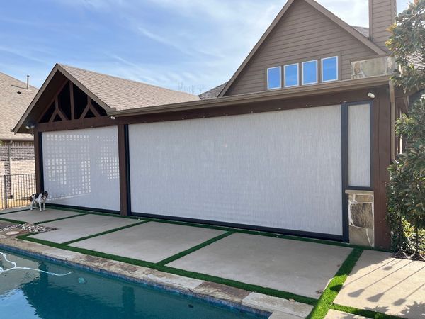 Backyard pool cabana with white privacy screens and a stone patio beside a swimming pool